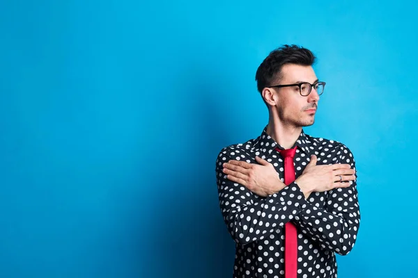 Portret van een jonge man in dotty shirt in een studio op een blauwe achtergrond. — Stockfoto