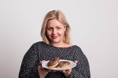 Donuts bir plaka üzerinde tutan bir çekici kilolu kadın Studio,.