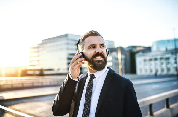 Hipster businessman with headphones in the city, listening to music. — Stock Photo, Image