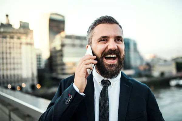 Смеющийся хипстерский бизнесмен со смартфоном в городе, делающий телефонный звонок . — стоковое фото