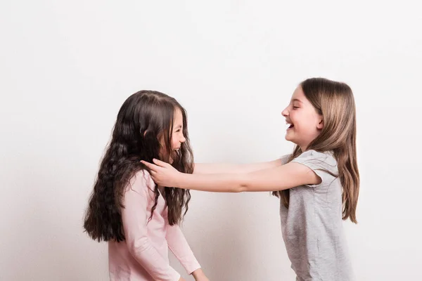 Dos niñas pequeñas de pie una frente a la otra en un estudio, riendo . — Foto de Stock