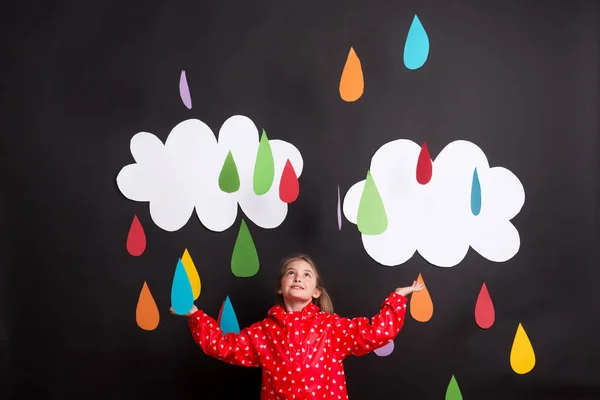 A small girl on a black background with clouds and raindrops. — Stock Photo, Image