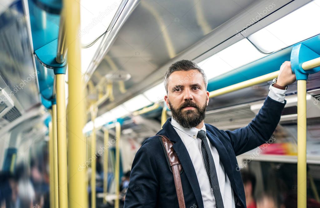 Hipster businessman inside the subway in the city, travelling to work.