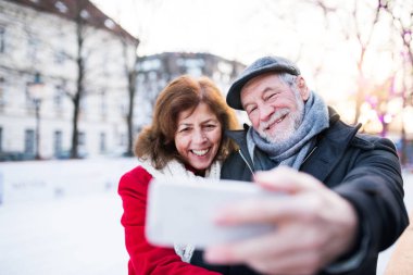 Kışın bir şehirde bir yolda smartphone ile üst düzey Çift.
