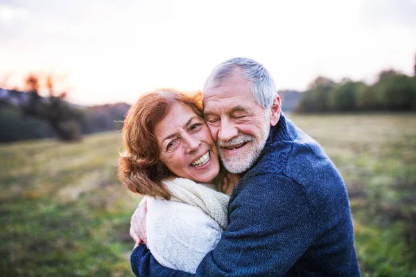 Seniorenpaar umarmt sich bei Sonnenuntergang in der herbstlichen Natur. — Stockfoto