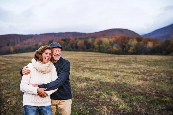 年长的夫妇拥抱在秋天自然在日落, 笑. — 图库照片
