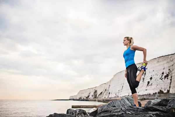 Genç sportif kadın runner kulaklık dışında sahilde uzanan ile. — Stok fotoğraf