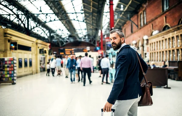 Hipster businessman with suitcase walking inside subway station in London. — Stock Photo, Image