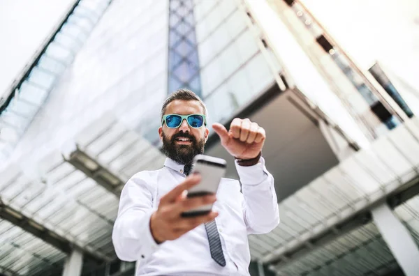 Hipster affärsman med smartphone stående på gatan i London, tar selfie. — Stockfoto