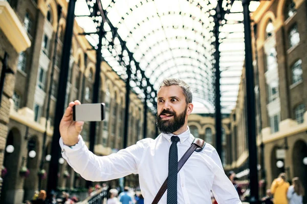 Businessman on the trian station in London, grimacing and taking selfie. — Stock Photo, Image