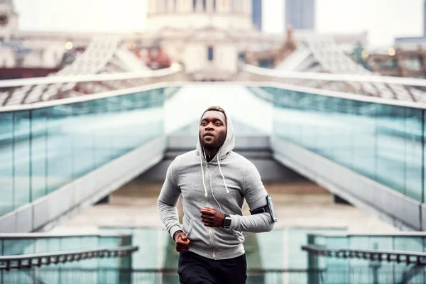 都市の外の橋の上を実行しているスポーティな若い黒人ランナー. — ストック写真