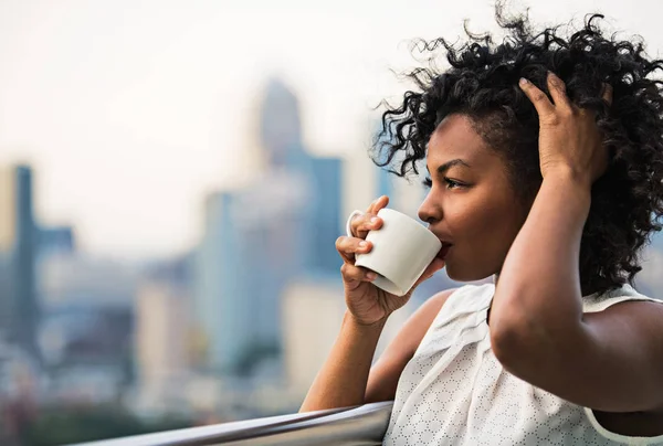 A close-up portrait of a woman standing on a terrace, drinking coffee. — Stock Photo, Image