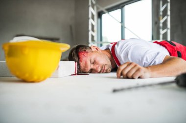 İnşaat alanı üzerinde kazadan sonra yerde yatarken bir bilinçsiz adam işçi.