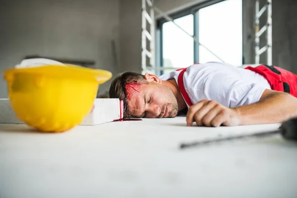 En medvetslös man arbetare liggande på golvet efter olycka på byggarbetsplatsen. — Stockfoto