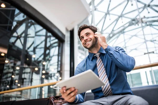 Un joven empresario con tablet y auriculares en un edificio moderno . — Foto de Stock