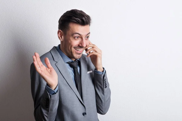 Portret van een jonge man van de vrolijke en verrast met een smartphone in een studio. — Stockfoto