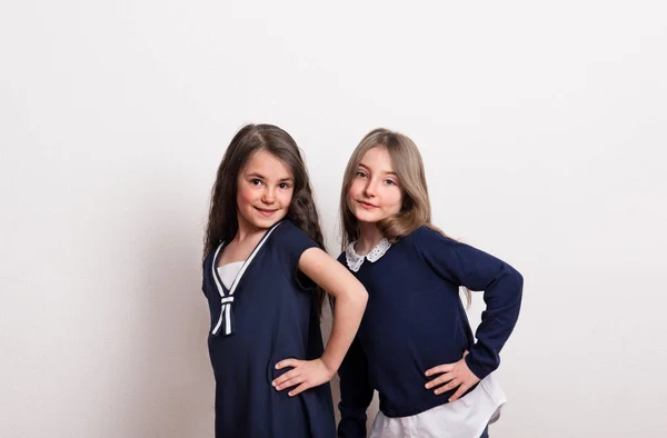 Deux petites écolières avec uniforme debout dans un studio . — Photo