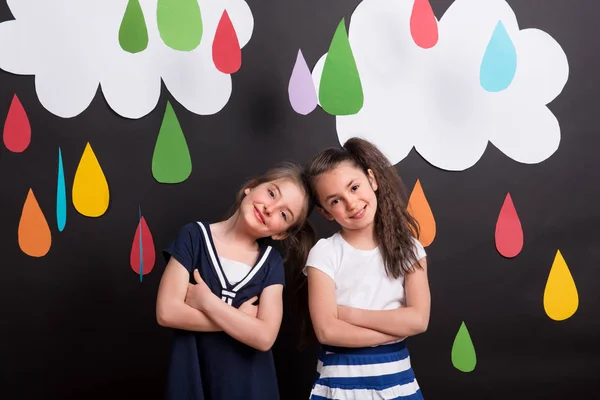 小女孩在演播室 站立反对黑背景与白云和五颜六色的雨滴 — 图库照片