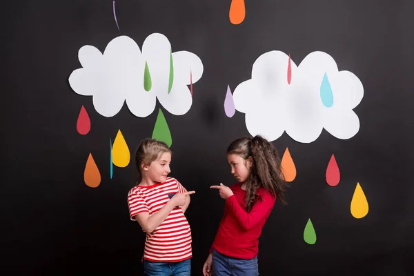 Kleine Mädchen im Atelier vor schwarzem Hintergrund mit Wolken und Regentropfen. — Stockfoto