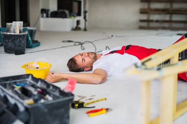 Een werknemer van de man op de vloer liggen na een ongeval op de bouwplaats. — Stockfoto