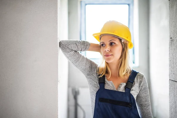 Jonge vrouw werknemer met een gele helm op de bouwplaats. — Stockfoto