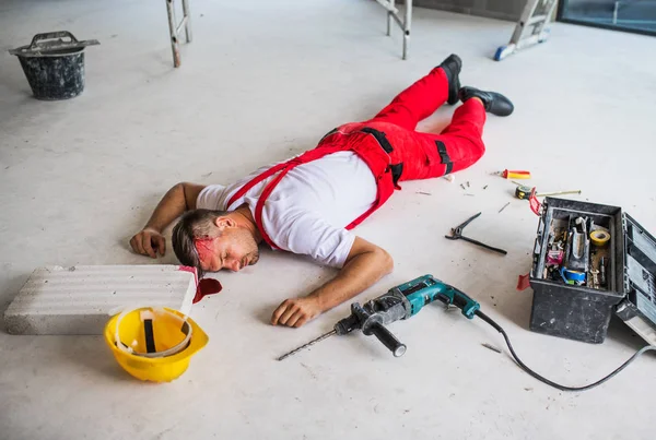 Ένας εργαζόμενος αναίσθητο άντρα ξαπλωμένο στο πάτωμα μετά από ατύχημα στο εργοτάξιο. — Φωτογραφία Αρχείου