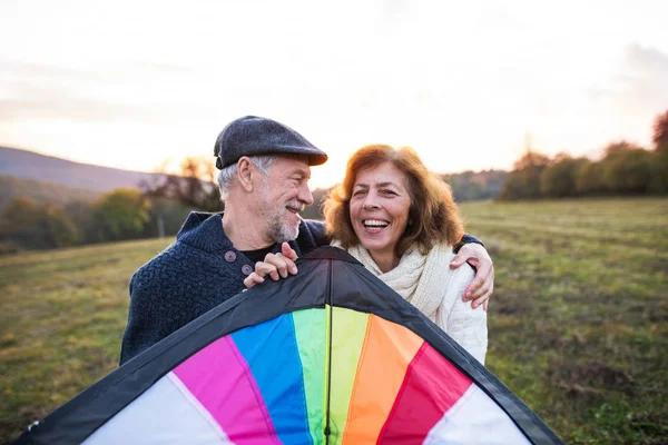 Homem sênior e uma mulher com um papagaio em uma natureza de outono . — Fotografia de Stock