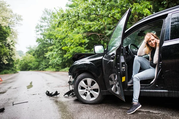 Jeune femme dans la voiture endommagée après un accident de voiture, passer un appel téléphonique . — Photo