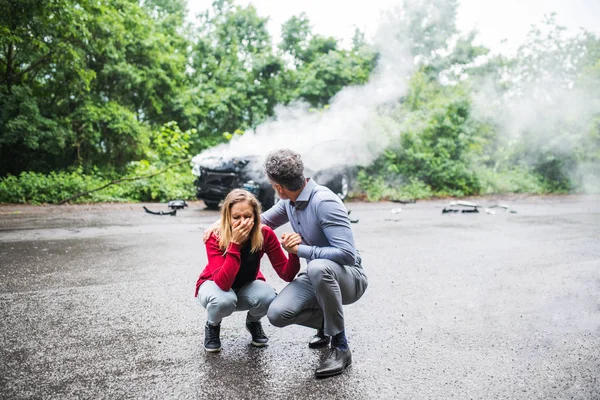 En mogen man pratar med en stressad ung kvinna efter en bilolycka. — Stockfoto