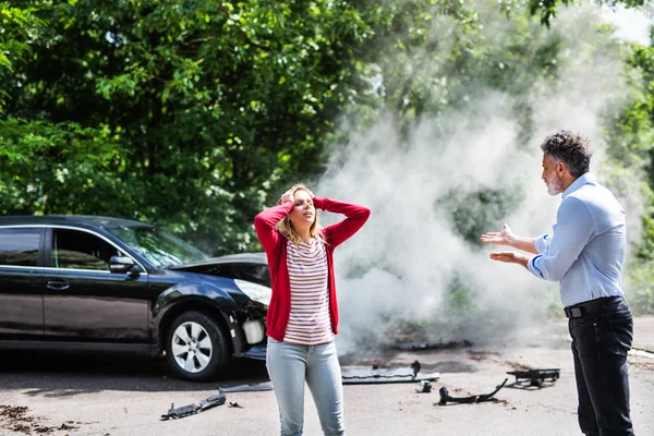 Злой зрелый мужчина и молодая женщина спорят после автомобильной аварии . — стоковое фото