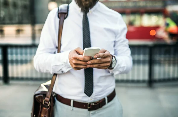 Unrecognizable businessman with smartphone standing on the street in city. — Stock Photo, Image