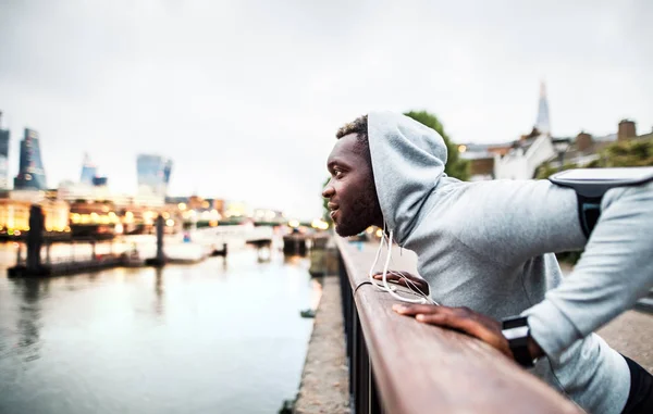 黑人赛跑者与智能手机在一个城市的桥梁臂章, 休息. — 图库照片