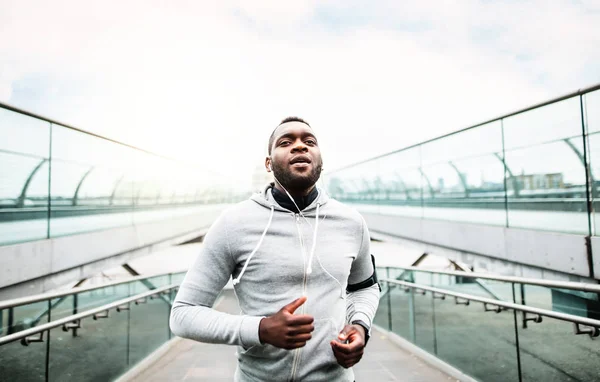 Молодий спортивний чорний чоловік біжить на мосту зовні в місті . — стокове фото