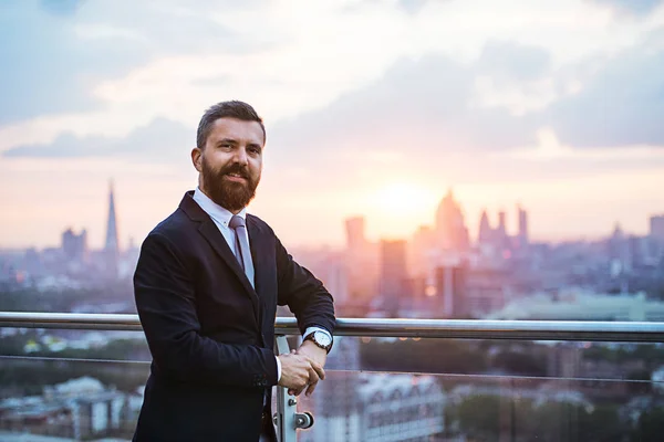 Επιχειρηματίας με σακάκι στέκεται ενάντια στην Λονδίνο πανοραμική θέα στο ηλιοβασίλεμα. — Φωτογραφία Αρχείου