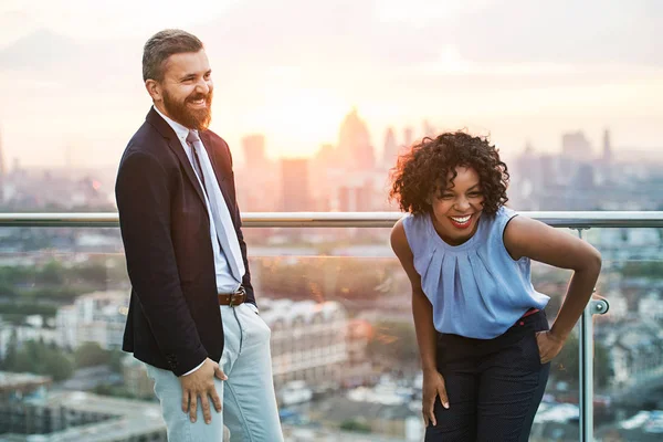 Två företagare står mot London utsikt vid solnedgången, skrattar. — Stockfoto