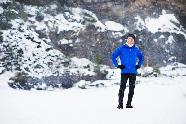 A full-length portrait of senior man standing after the run in winter nature. — Stock Photo, Image