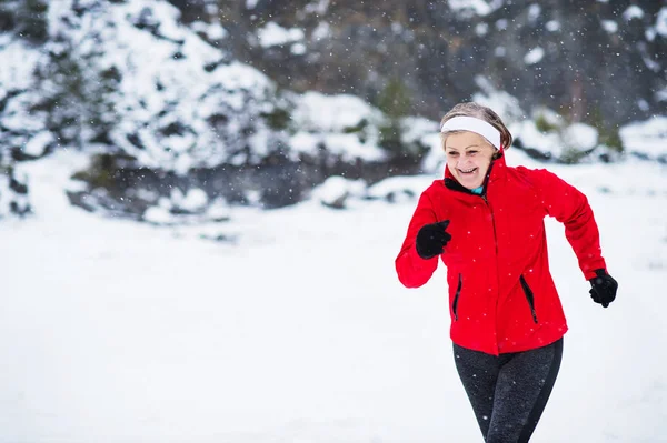 Senior Kvinna jogging i vinter natur. Kopiera utrymme. — Stockfoto