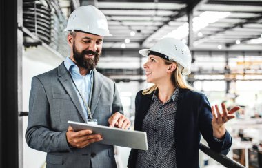 Bir portresini endüstriyel erkek ve kadın mühendis bir fabrikada tablet ile çalışma.