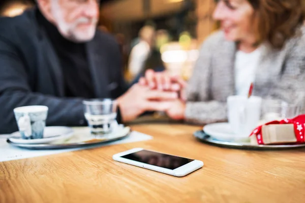 Senior para ze smartfonem w kawiarni. Czas Bożego Narodzenia. — Zdjęcie stockowe