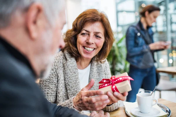 Senior paar met een cadeautje in een café. Kersttijd. — Stockfoto