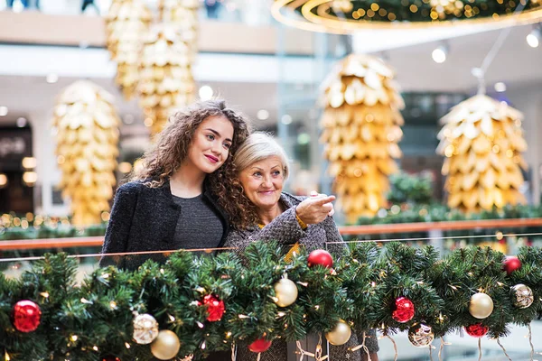 Een portret van een grootmoeder en tiener kleindochter in shopping center op Kerstmis. — Stockfoto