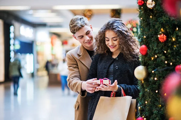 Un giovane uomo che fa un regalo alla sua ragazza nel centro commerciale a Natale . — Foto Stock