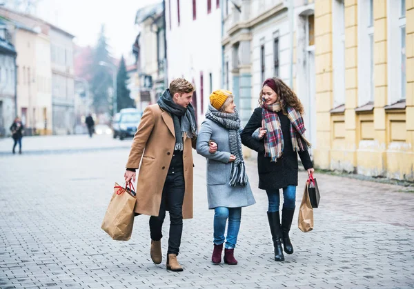 Grand-mère et petits-enfants adolescents avec des sacs marchant dans la rue en hiver . — Photo