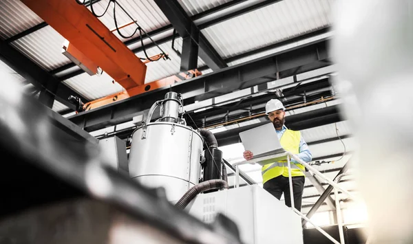 Una vista de bajo ángulo de un ingeniero industrial con portátil en una fábrica, trabajando . — Foto de Stock