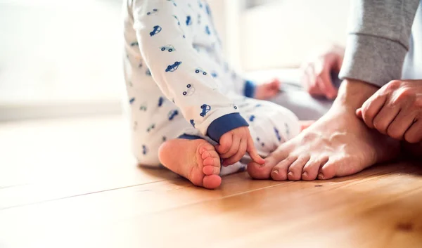 Ο πατέρας με ένα μικρό παιδί αγόρι κάθεται στο πάτωμα στην κρεβατοκάμαρα στο σπίτι. — Φωτογραφία Αρχείου