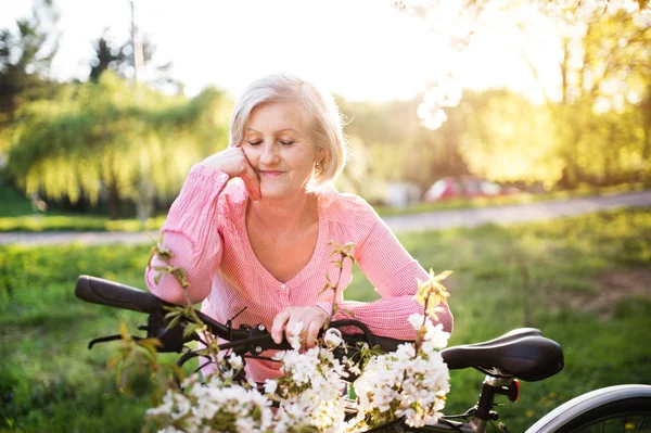 Vacker äldre kvinna med cykel utanför i vår natur. — Stockfoto