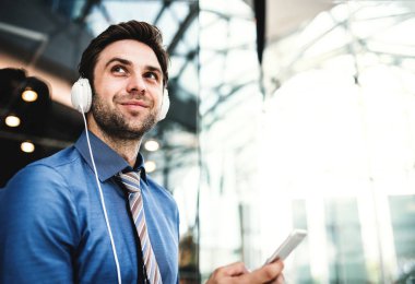 Genç bir işadamı ile akıllı telefon ve kulaklık modern bir binada.