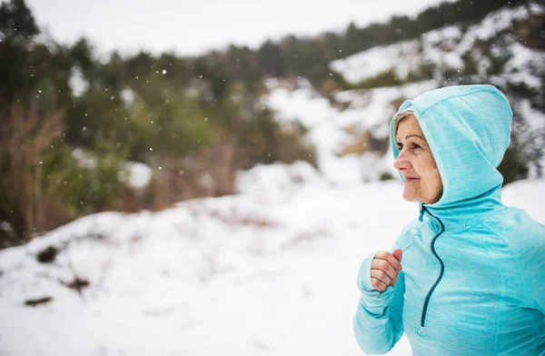 Glückliche Seniorin joggt in winterlicher Natur. — Stockfoto