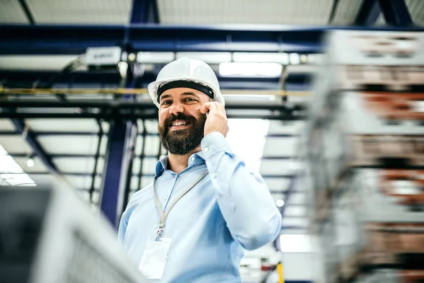 Ett porträtt av ingenjör industriell mannen med smartphone i en fabrik. — Stockfoto