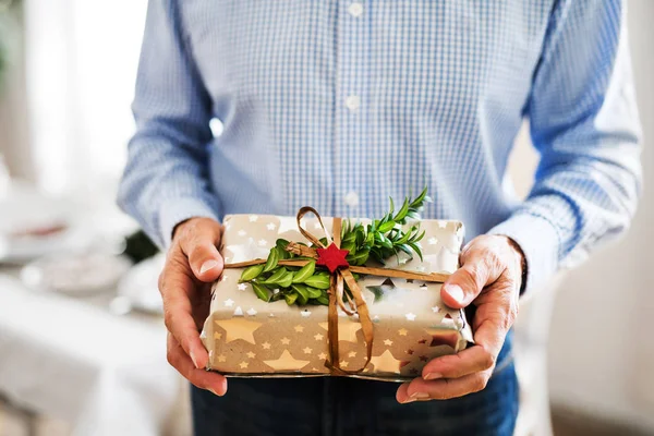 Un homme âgé méconnaissable tenant un cadeau enveloppé au moment de Noël . — Photo